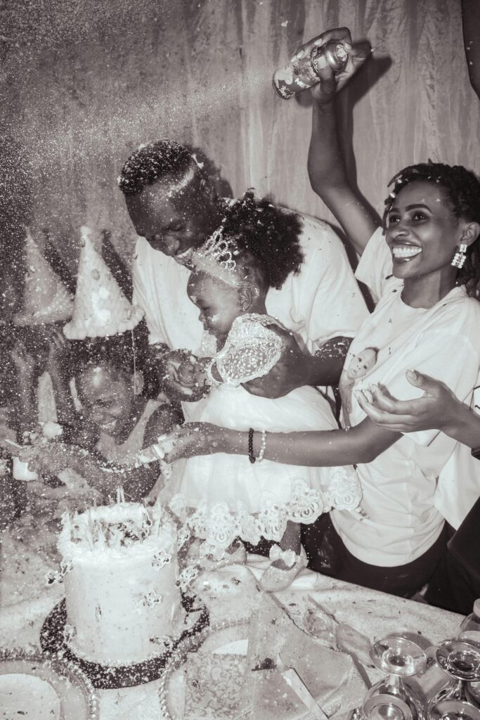 Happy family celebrating a birthday with cake and confetti indoors. Laughter and joy fill the atmosphere.