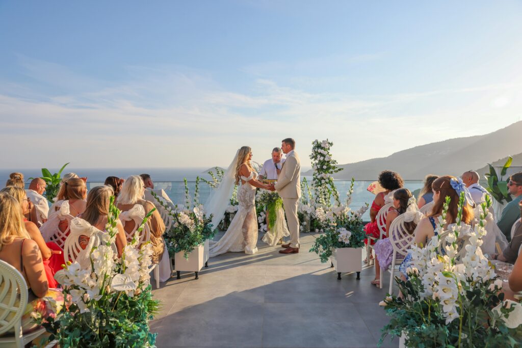 Elegant outdoor wedding ceremony with ocean view and floral decor.